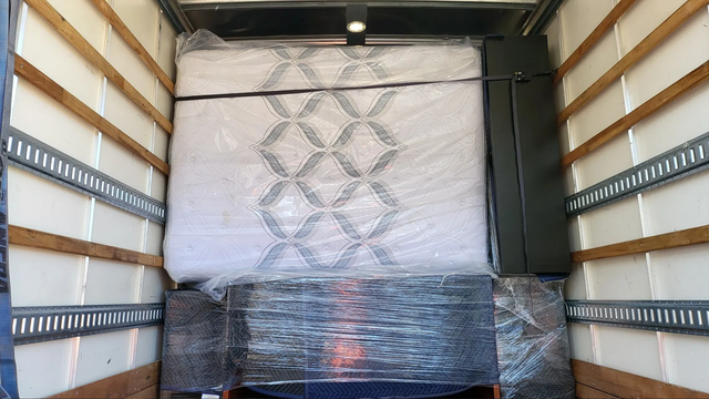 A mattress wrapped upright among protected belongings in a moving truck